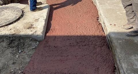 Red concrete being poured over utility lines